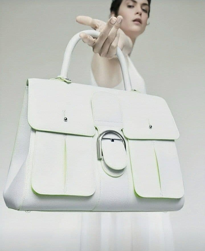 Woman holding a white statement handbag with a circular buckle